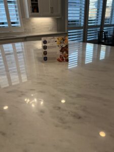 Technician applying MORE® AntiEtch® to a honed marble countertop in a luxury kitchen in Southlake, TX.