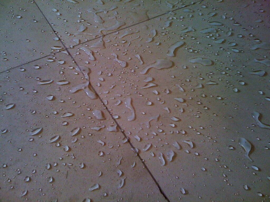 Water beading on a newly sealed limestone floor, showcasing Sureshine’s protective sealing service