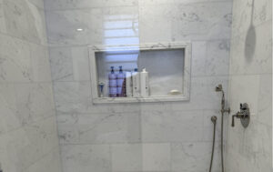 Hard water deposits and soap buildup on a marble shower wall before restoration in Laguna Niguel California.