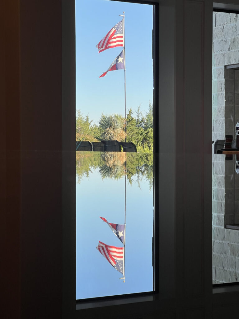 Reflection of the Texas and American flags on a perfectly polished, AntiEtched countertop in Texas, showcasing superior protection and shine.