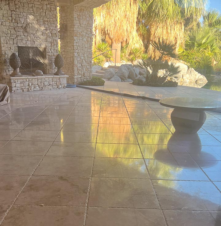 Restored and sealed travertine patio in a Ladera Ranch backyard, reflecting light and tropical foliage after polishing by Sureshine Care and Restoration Services, Inc.