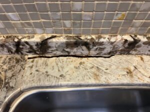 Sureshine technician repairing a granite sink rail crack in a Newport Beach kitchen