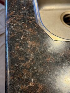 Sureshine technician performing granite crack repair in Brentwood, CA — restoring sink rail and seam with color-matched stone adhesive for a flawless finish.