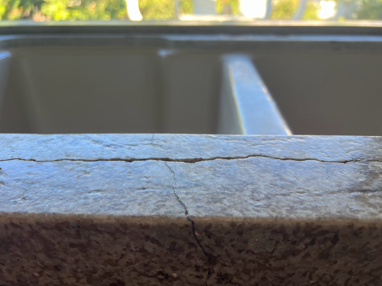 Granite countertop crack repair by Sureshine Care and Restoration Services, Inc., showing restored strength and a seamless finish after repairing a sink-rail crack.