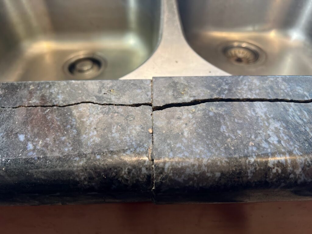 Granite countertop crack repair near a kitchen sink with polished, seamless finish after rodding removal.